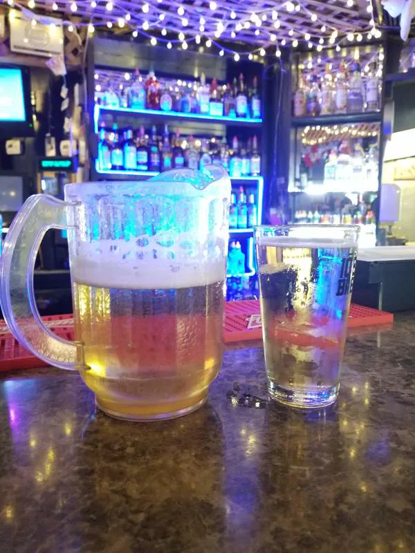 A pitcher and pint of beer on the B&B Lounge bar under blue back-bar lights and string lights