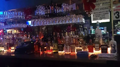 The empty back-bar at Bialystok, with underlit bottles, hanging glassware, and a handwritten specials board