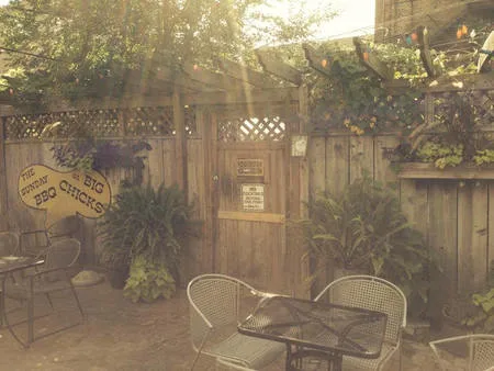 The empty Big Chicks patio, wooden fence, and Sunday BBQ at Big Chicks speech-bubble sign