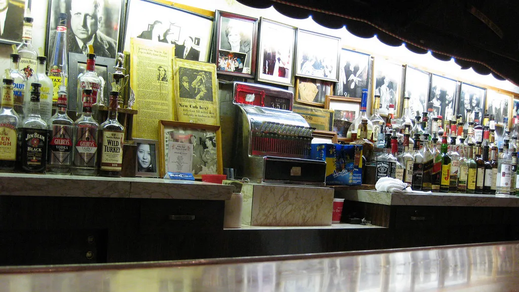 The cluttered back bar, cash register, and framed clippings at Billy Goat Tavern
