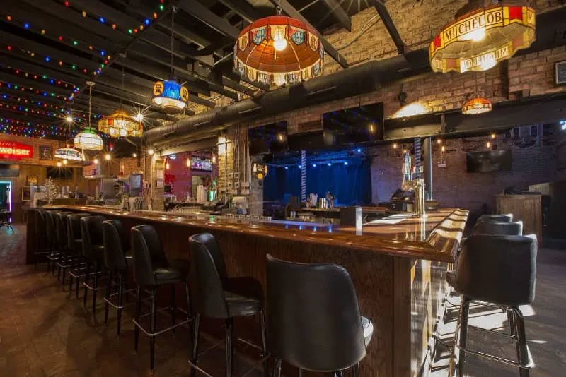 The empty bar rail, Tiffany lamps, and stage at Carol's Pub