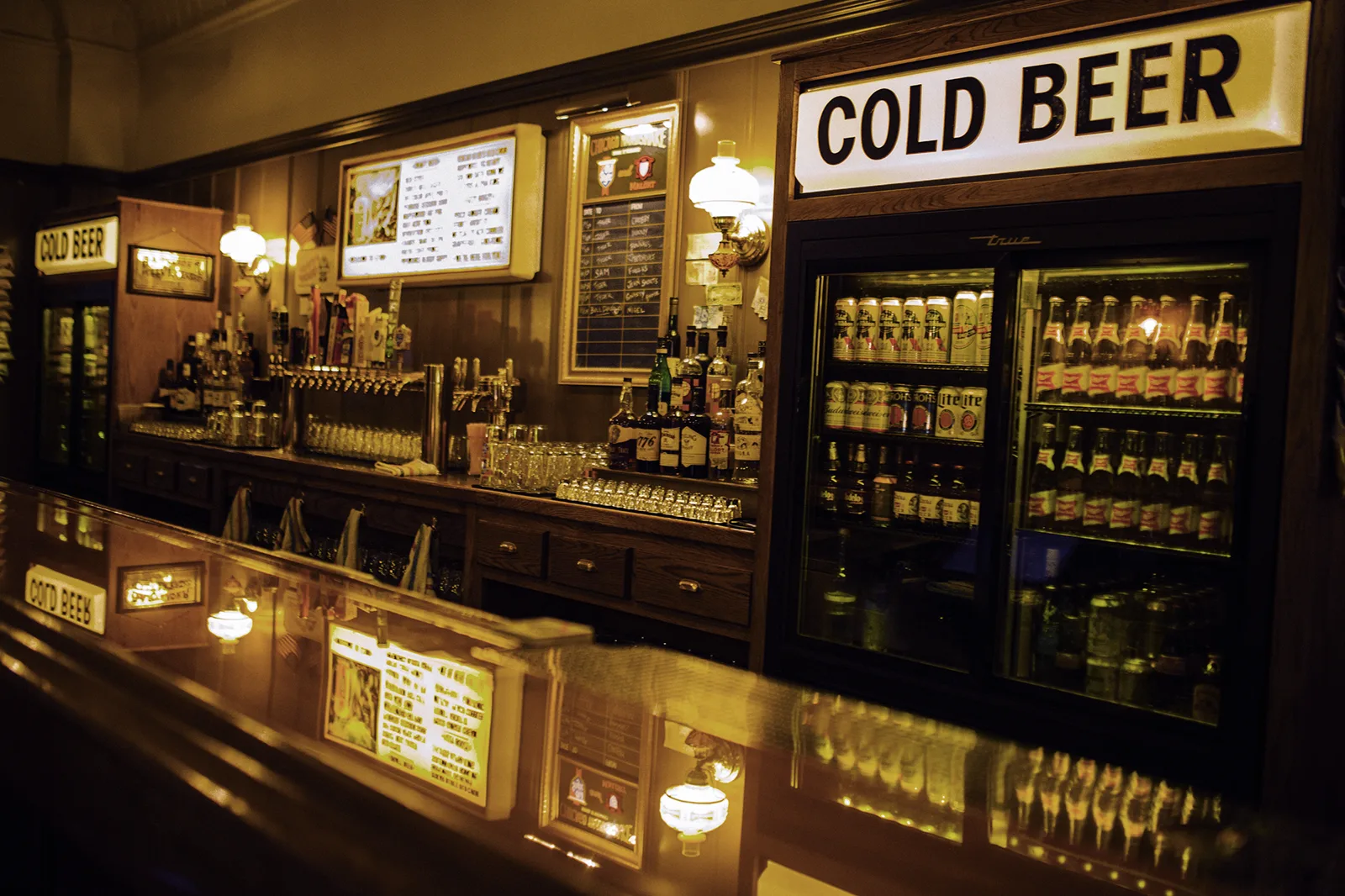 The empty EZ Inn rail, True cooler, silver taps, and COLD BEER lightbox