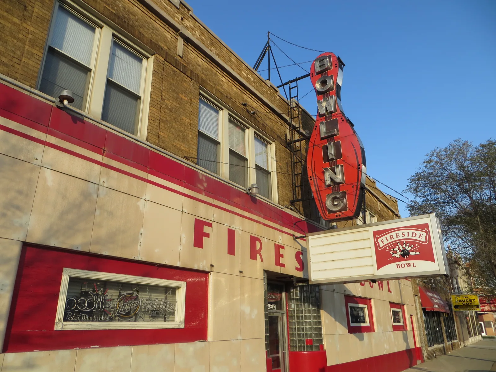 The Fireside Bowl bowling-pin sign, cream panels, and beer-neon window from the sidewalk