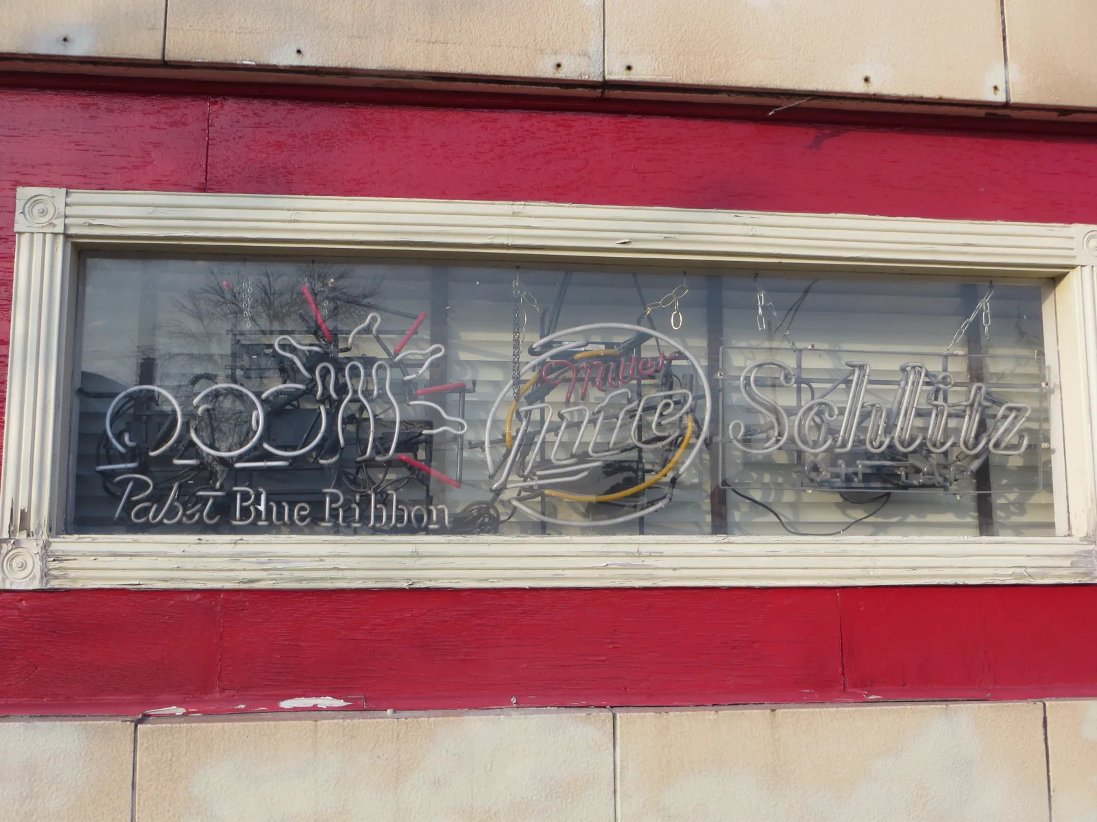 Pabst, Miller Lite, and Schlitz neon in a red-framed Fireside Bowl storefront window