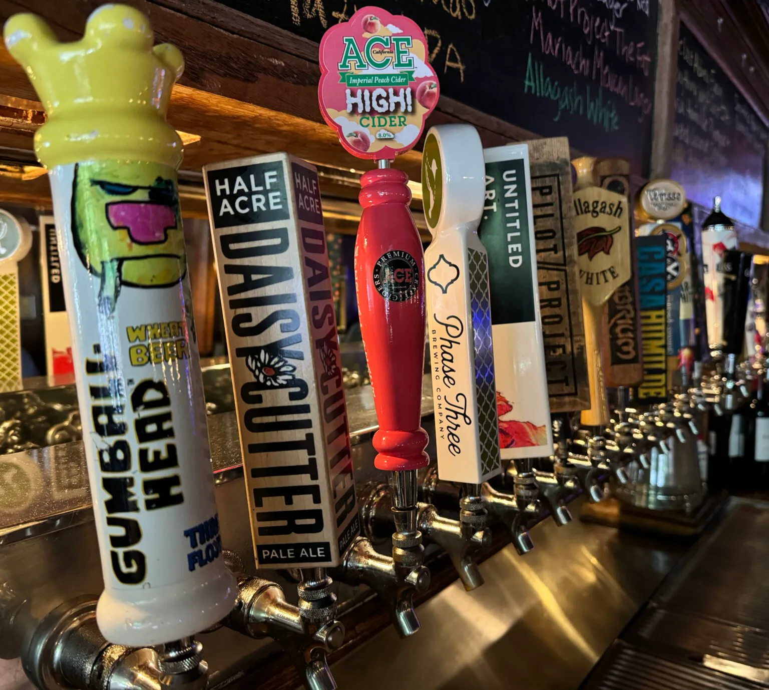 A row of Chicago draft handles along the Kasey's Tavern rail, with a chalkboard beer list behind