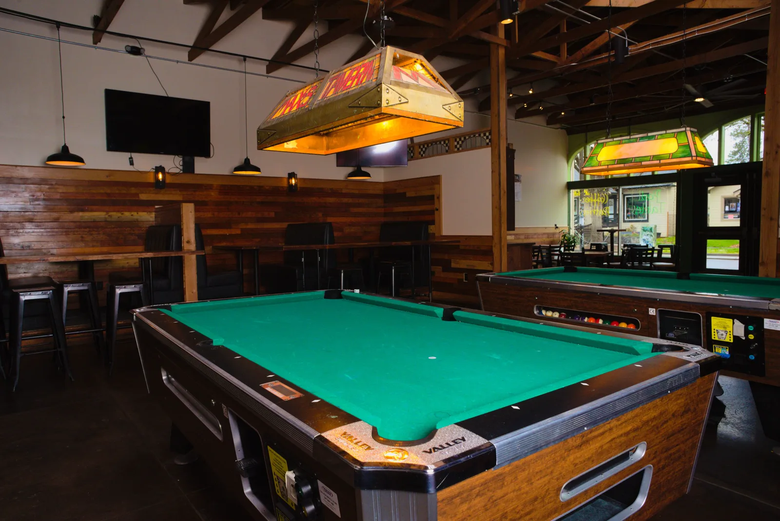 Two Valley pool tables under MAX'S TAVERN stained-glass lamps in the expanded room