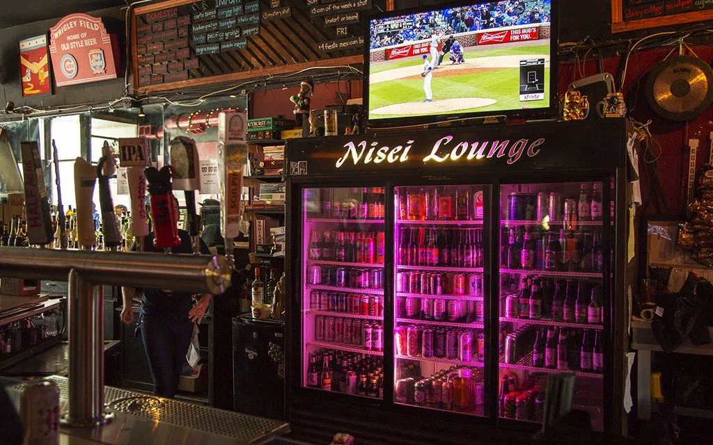 The beer cooler and cursive Nisei Lounge sign behind the bar