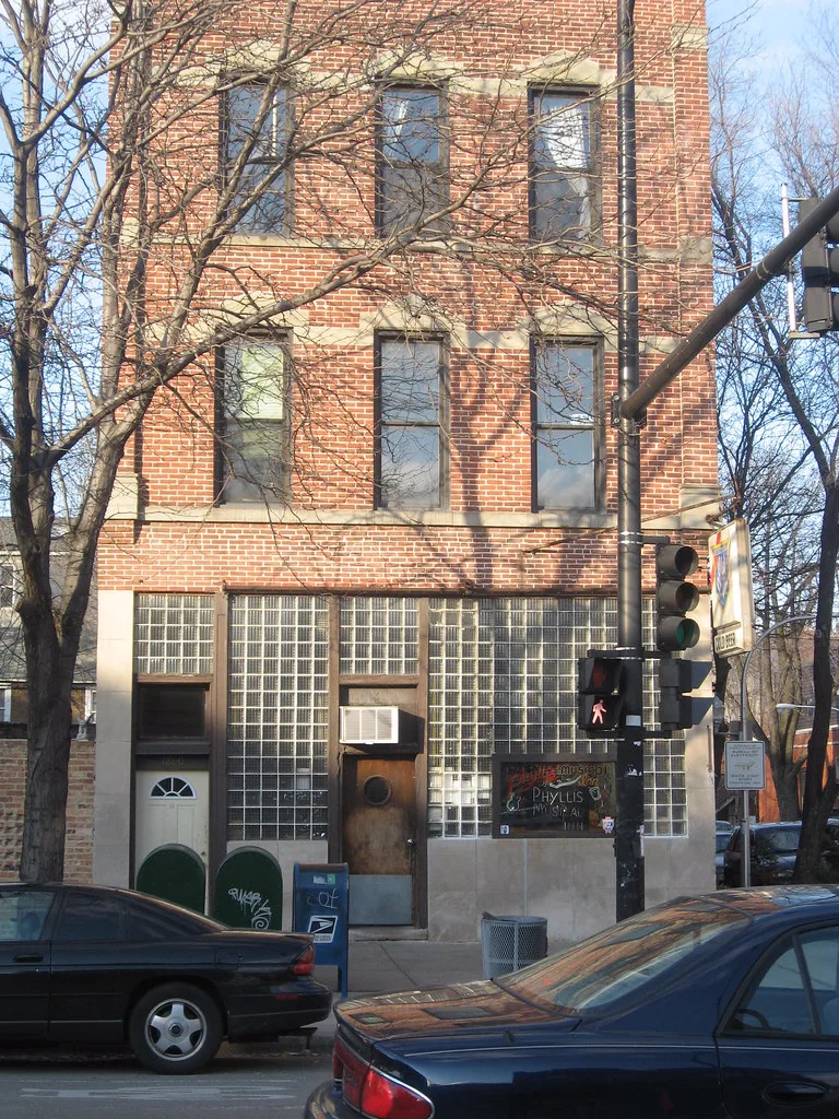 The glass-block storefront, porthole door, and 1800 address at Phyllis' Musical Inn