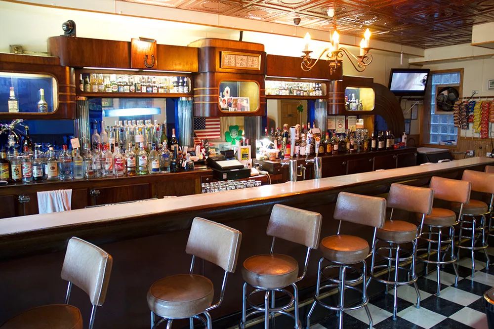 The dark-wood back bar, tan stools, and liquor shelves at Question Mark Bar