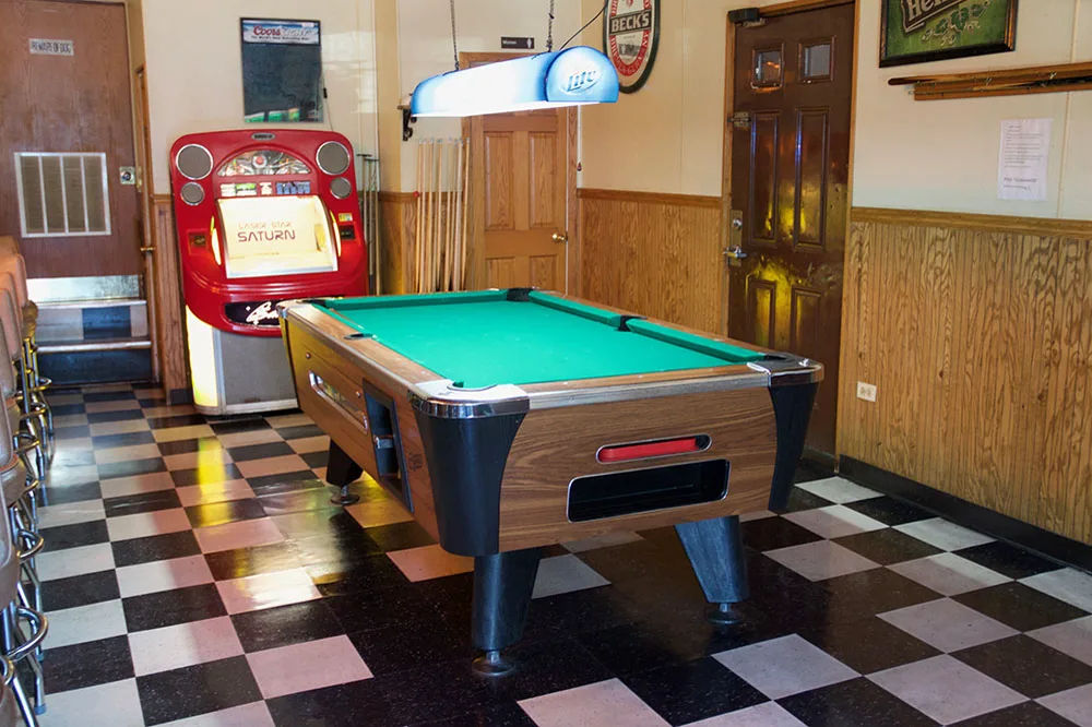 The green pool table, red jukebox, and beer signs in the Question Mark Bar game room