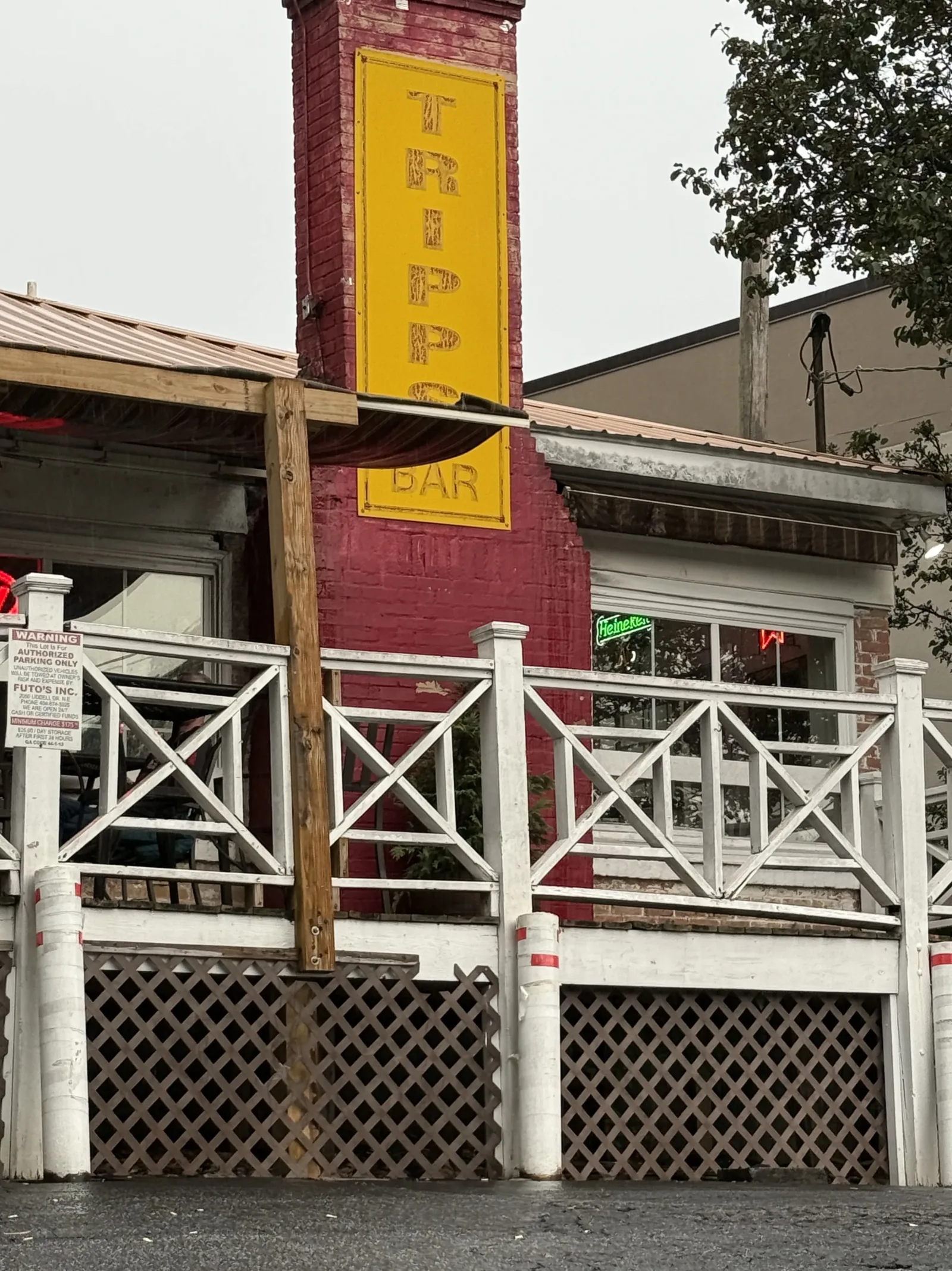 Yellow vertical Tripps Bar sign on the red chimney above the wooden deck in Atlanta